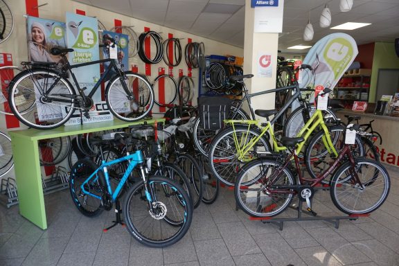 ein blaues, ein Lindgrünes, ein rotes und ein grauen Fahrrad sind zu sehen. sie stehen auf dem Boden und auf Fahrradständern. 