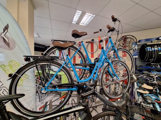 Blaue Fahrräder stehen auf einem Verkaufsständer im Geschäft. Die Sattel sind braun.