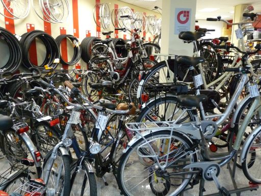 Im Vordgrund sind Kundenfahrräder zu sehen vor eine Wand, die mit Reifen und Felgen bestückt ist. 