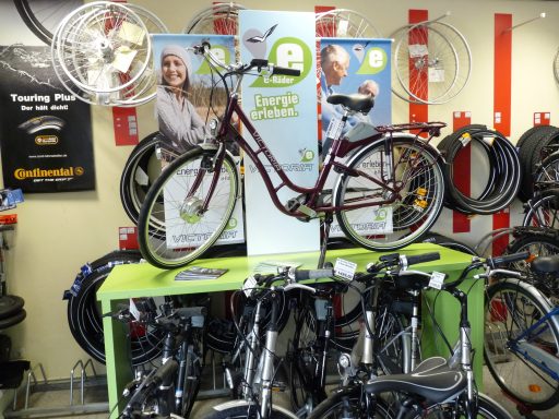 Ein rotens Damen City-Bike ist auf einem leuchtend hellgrünen Fahrradständer. 